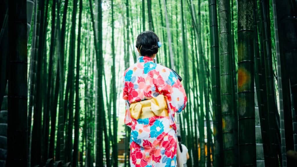 Kvinna i kimono bland bambuträd.
