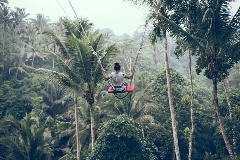 Kvinna gungar över regnskog.