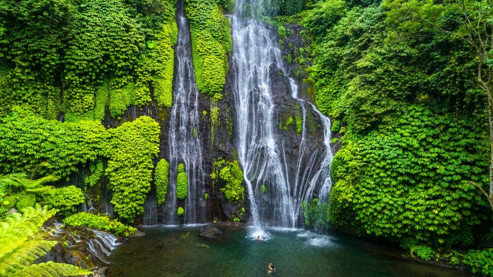 Beautiful Sekumpul Waterfallin bali, indonesia with people swimming.