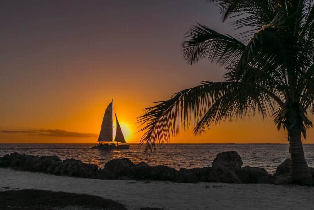 Segelbåt i horisonten framför solnedgång.