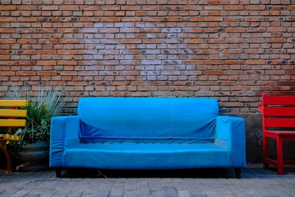 Blå soffa mot tegelvägg.