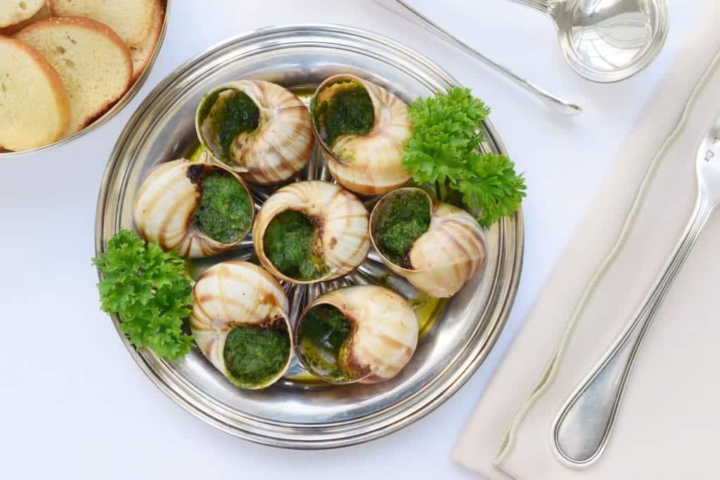Escargot snials in garlic on a plate.