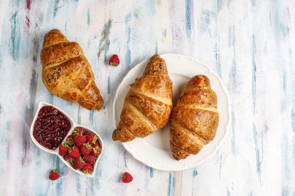 Freshly baked croissants with raspberry jam and raspberry fruits