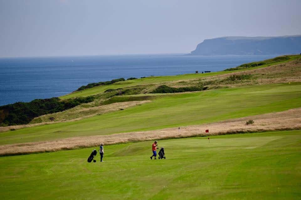 Two people playing golf and walking on the course of Royal Tarlair.